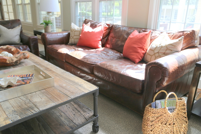 brown leather sofa with orange pillows