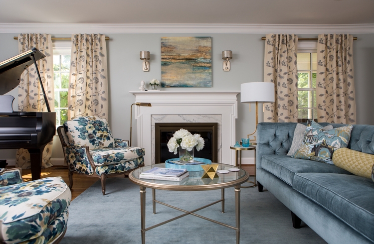 light blue living room walls with blue velvet sofa and round coffee table and pair of blue floral chairs design by Kristie Barnett, The Decorologist