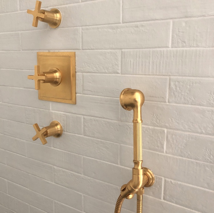 gold shower fixtures and brick tile shower wall in bathroom by Kristie Barnett