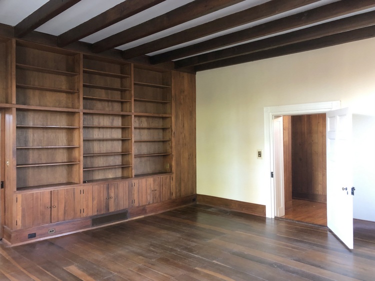 dark paneling library with wood stain beams