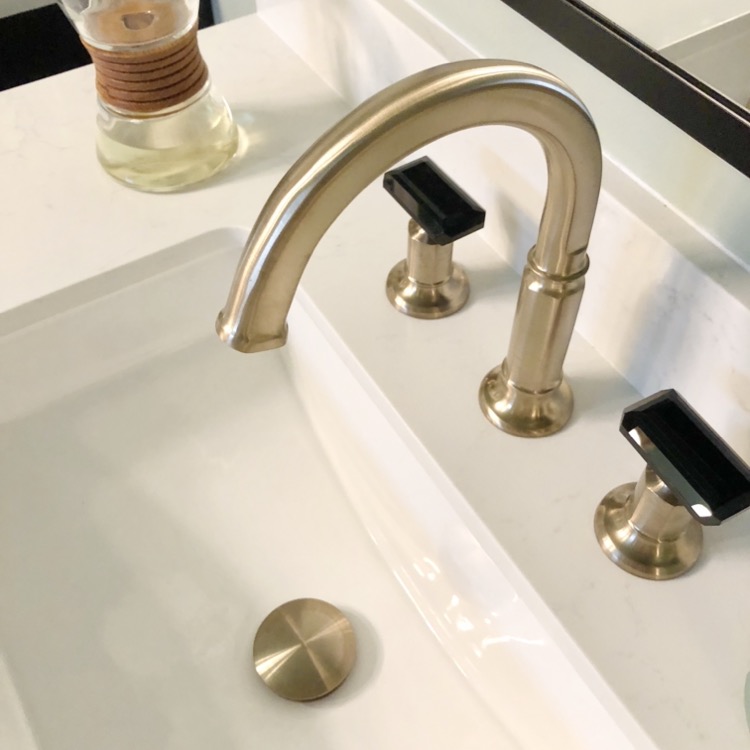 gold bathroom faucet with black handles
